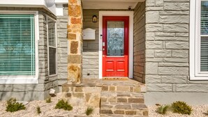 A house with a stone facade, a red door, and a small porch with steps.