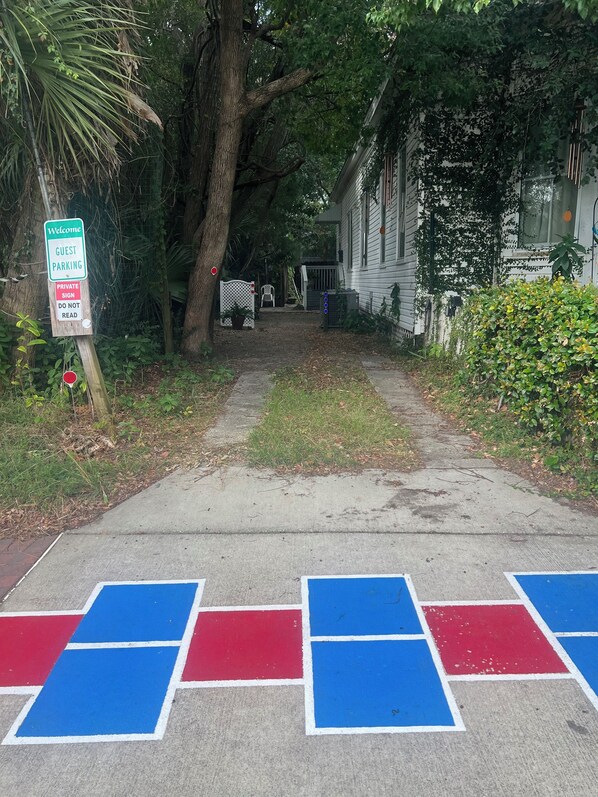 A pathway leading to a house with a 'Welcome Guest Parking' sign, a private sign, and a 'Do Not Read' sign.