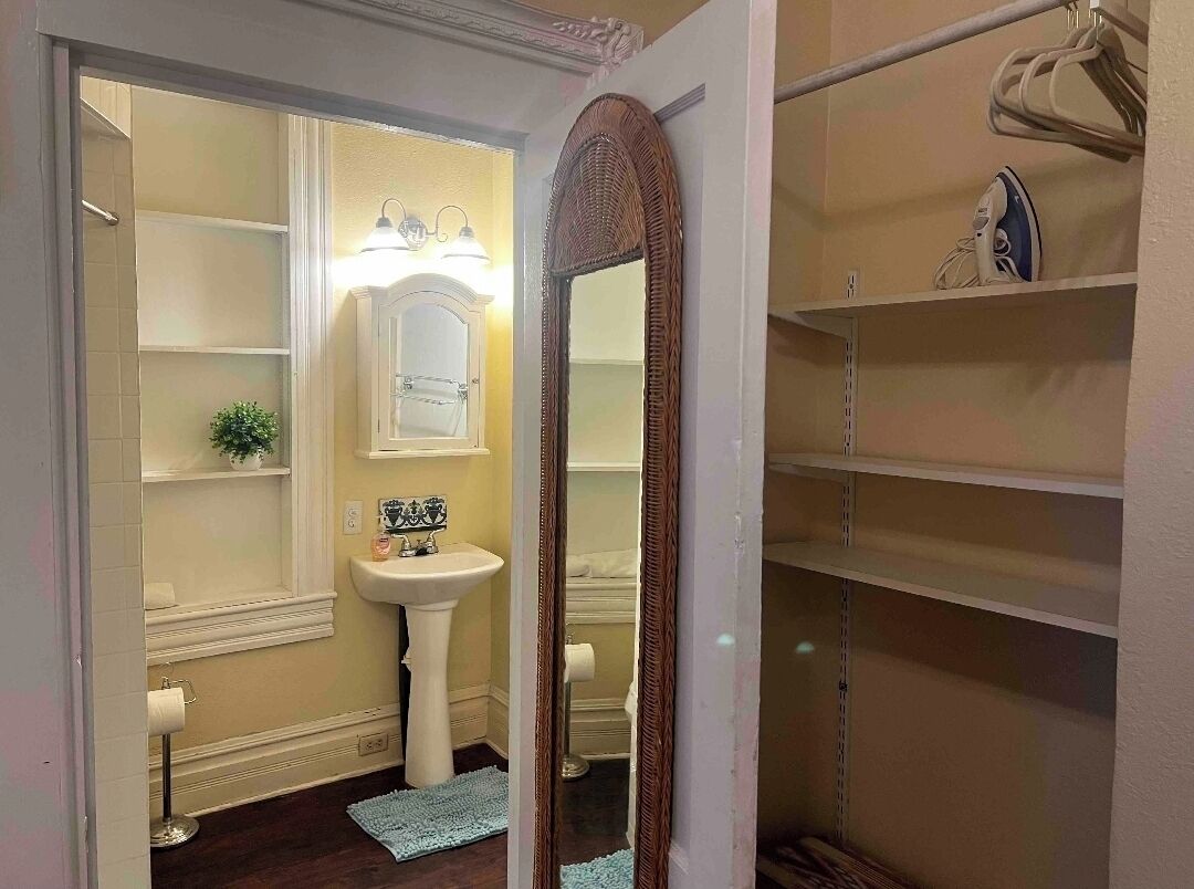 A bathroom with a white sink, mirror, and shelves.