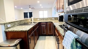 A modern kitchen with granite countertops, stainless steel appliances, and wooden cabinetry. - Spacious 7 BD walk to the beach + pool (North Myrtle Beach)