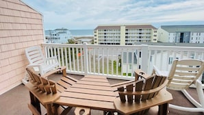 A balcony with wooden furniture and a view of the ocean and buildings. - Spacious 7 BD walk to the beach + pool (North Myrtle Beach)