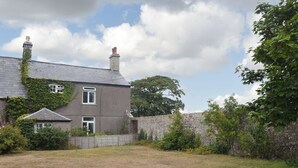 A two-story house with a stone wall and a grassy yard.