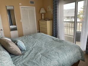 Un dormitorio con cama, cómoda, espejo y vistas al exterior.