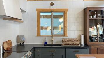 A modern kitchen with dark cabinets, a stainless steel oven, and a wooden countertop.