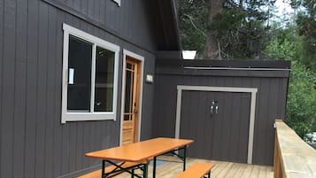 A deck with picnic tables and a door, surrounded by a dark wooden fence.