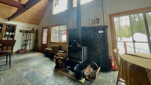 Ein gemütliches Zimmer mit Kamin, Holzbalken und großen Fenstern.