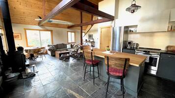 A cozy living area with a sofa, chairs, a coffee table, and a kitchen with a stove and refrigerator.