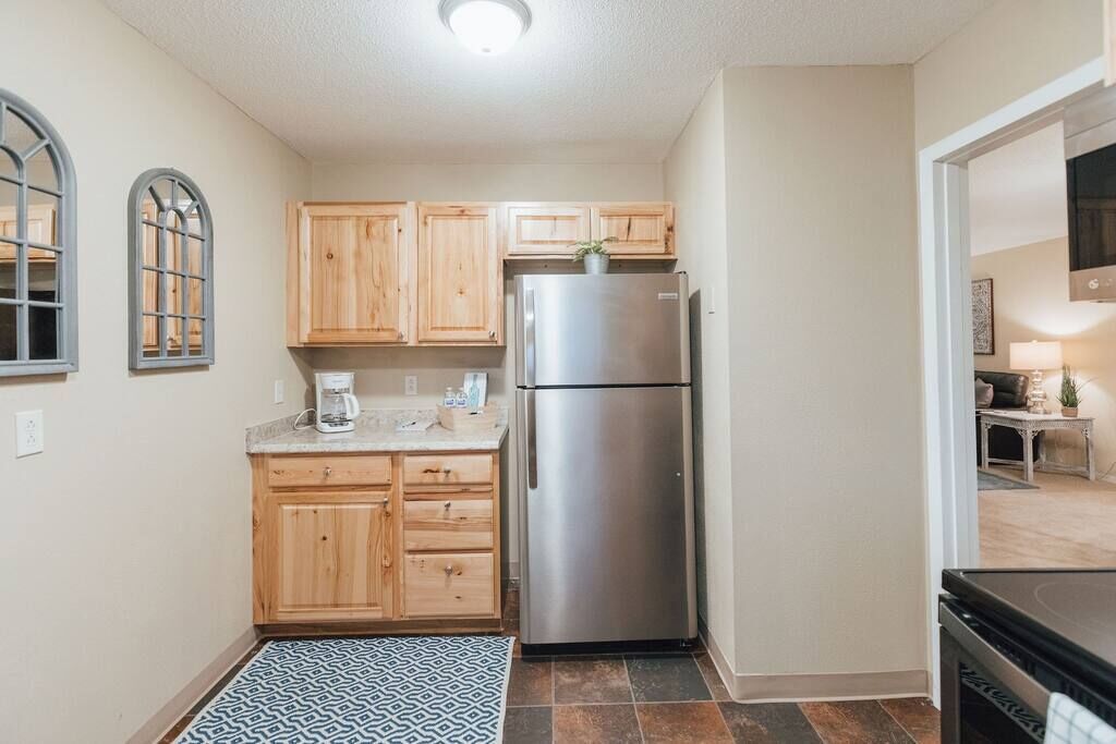 A compact kitchen with wooden cabinets, a stainless steel refrigerator, and a coffee maker on the countertop.