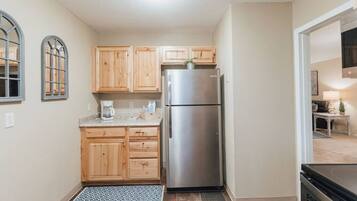 A compact kitchen with wooden cabinets, a stainless steel refrigerator, and a coffee maker on the countertop.