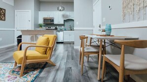 A modern kitchen with white cabinets, a central island, and a dining area with wooden chairs and a table. - Pet-Friendly Loft Downtown Near Dining & Parks 203 (Johnson City)
