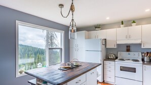 A modern kitchen with white cabinets, a wooden countertop, and a large window offering a view of a forest. - 3 Bed/2 Bath Home w/amazing views, BBQ, laundry, close to village & trails (Star Mountain)