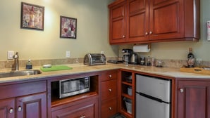 A kitchen with wooden cabinets, a stainless steel refrigerator, a microwave, a toaster, and a coffee maker.
