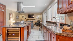 Une cuisine moderne dotée d’un grand îlot central, d’un four encastré et d’un coin repas avec un canapé et des chaises.