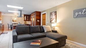 Un salon moderne avec un canapé d’angle, une table basse et un coin repas à l’arrière-plan.