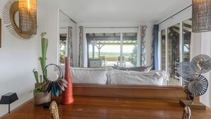 A modern living room with a wooden bench, a large window, and a view of the outdoors. - Villa Priva • Meilly Estate (Saint-Louis)