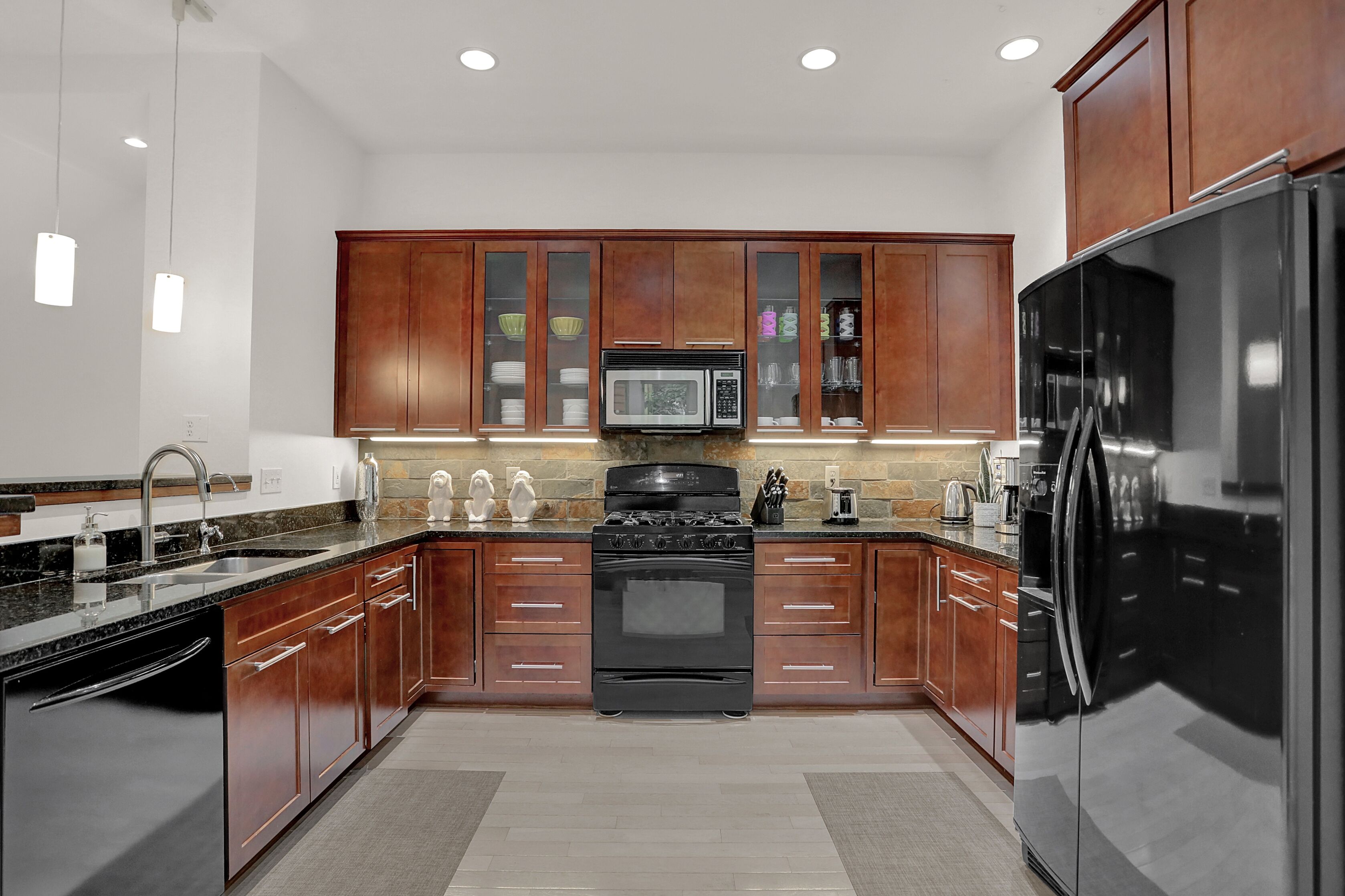 Una cocina moderna con armarios de madera, un refrigerador de acero inoxidable, un microondas y una estufa.