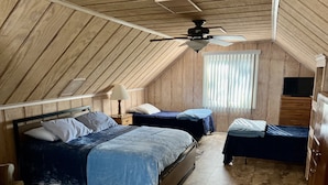 Ein Schlafzimmer mit zwei Betten, einem Deckenventilator, einem Fenster mit Jalousien und einer Holzkommode.