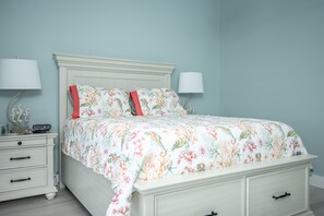 Quarto com cama, mesas de cabeceira e luminárias.