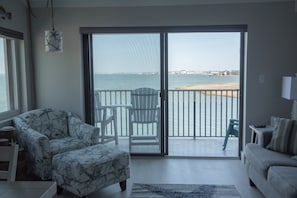 Relax in this stylish living room with a sofa, armchair, and ottoman, and step out onto the balcony for a breathtaking view of the beach and sea.
