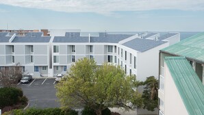 Un immeuble à plusieurs étages avec un parking et un arbre au premier plan.