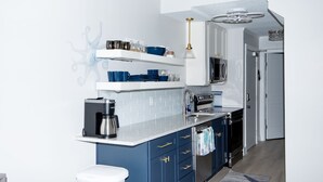 Une cuisine moderne avec des meubles bleus, un plan de travail blanc et un four à micro-ondes encastré.
