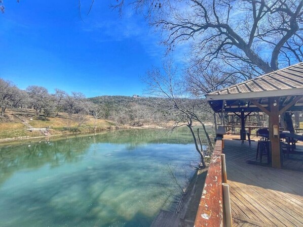 A clear outdoor swimming pool with a wooden deck and a gazebo.
