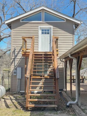 A single-story building with a front porch and a wooden staircase leading to a door.