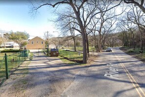 A road named 'River Road' with a gravel path alongside, a fenced area, and a building in the background.
