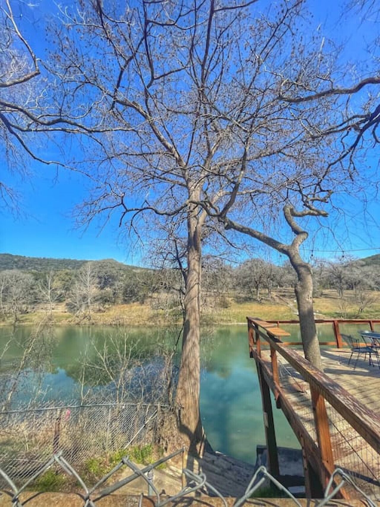 A wooden deck overlooking a calm lake with a clear sky.