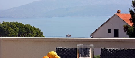En balkon med et bord dækket til to, en skål med frugt og et lys.