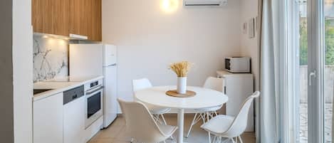 A modern kitchen with white appliances, a marble backsplash, and a dining area with a white table and chairs.