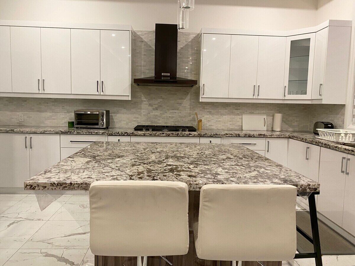 A kitchen with white cabinets, a granite countertop, and a built-in stove.