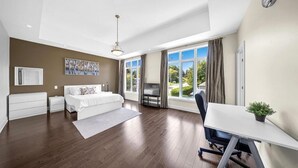 A modern bedroom with a large bed, a desk, and a view of the outdoors. - Dazzling Home Next to Beach & Go Station (Pickering)