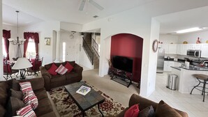 Ein geräumiges Wohnzimmer mit Kamin, ein Essbereich mit einer Chandelüster und eine Küche mit modernen Geräten.