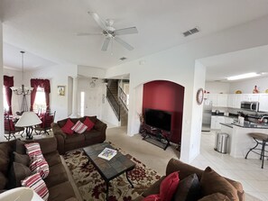 Ein geräumiges Wohnzimmer mit Kamin, ein Essbereich mit einer Chandelüster und eine Küche mit modernen Geräten.