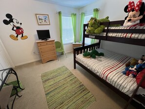 Una habitación infantil con literas, cómoda, televisor y decoración de Mickey y Minnie Mouse.