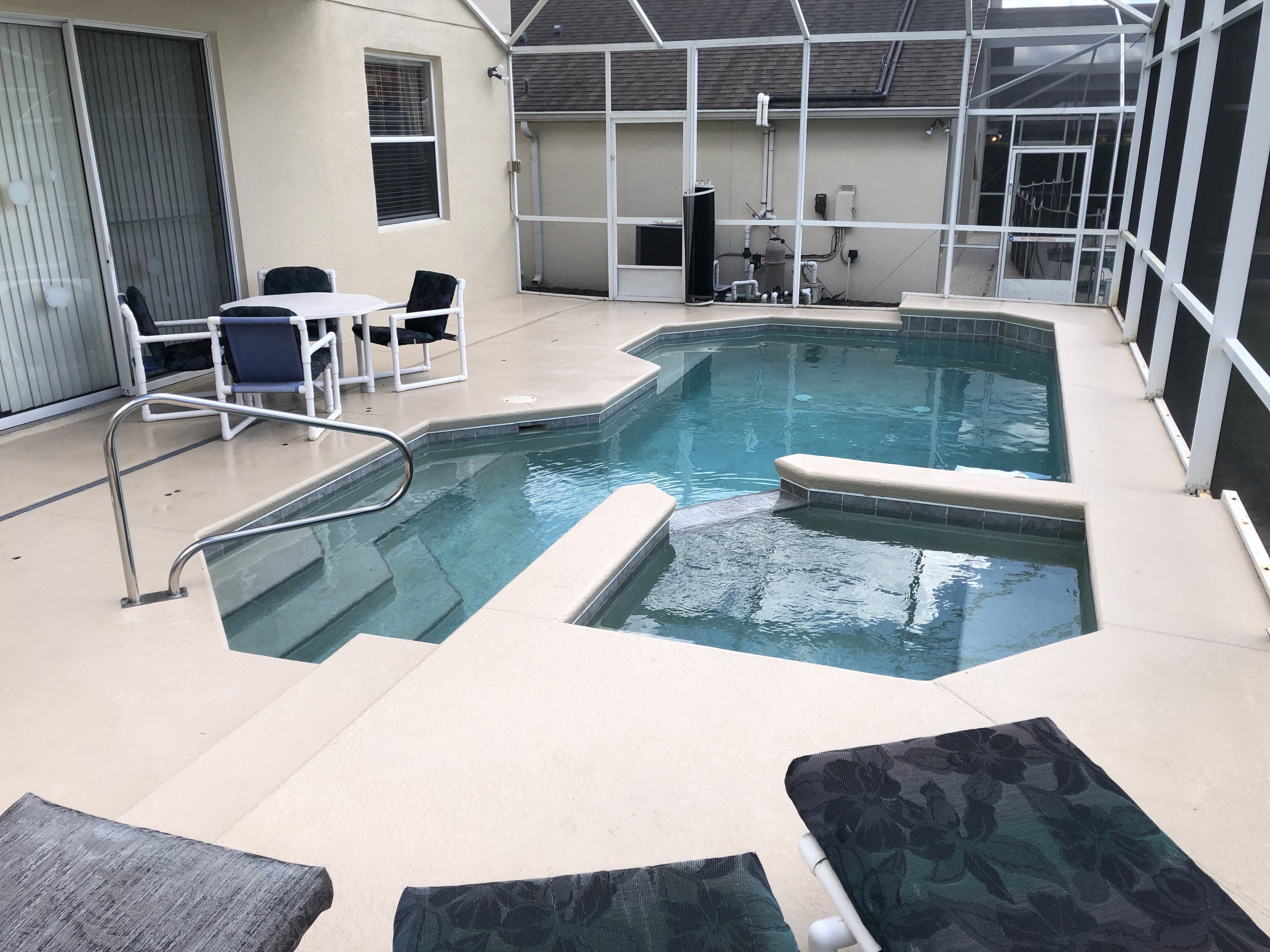 Une piscine intérieure dotée d’une terrasse carrelée, de quelques chaises longues et d’un espace abrité avec une table et des chaises.