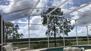A covered outdoor area with a pool, lounge chairs, and a view of a golf course. - 5 Bedroom, Pool Home Overlooking Golf Course. Close to Attractions (Davenport)