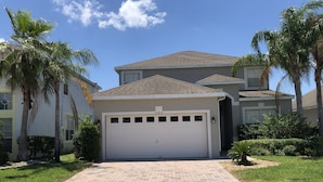 A residential house with a garage, surrounded by palm trees and a paved driveway. - 5 Bedroom, Pool Home Overlooking Golf Course. Close to Attractions (Davenport)