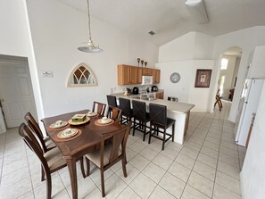 A spacious kitchen with a dining area, featuring a large island, wooden cabinets, and a microwave. - 4 bedroom  single story house with south facing pool and spa close to Disney (Kissimmee)