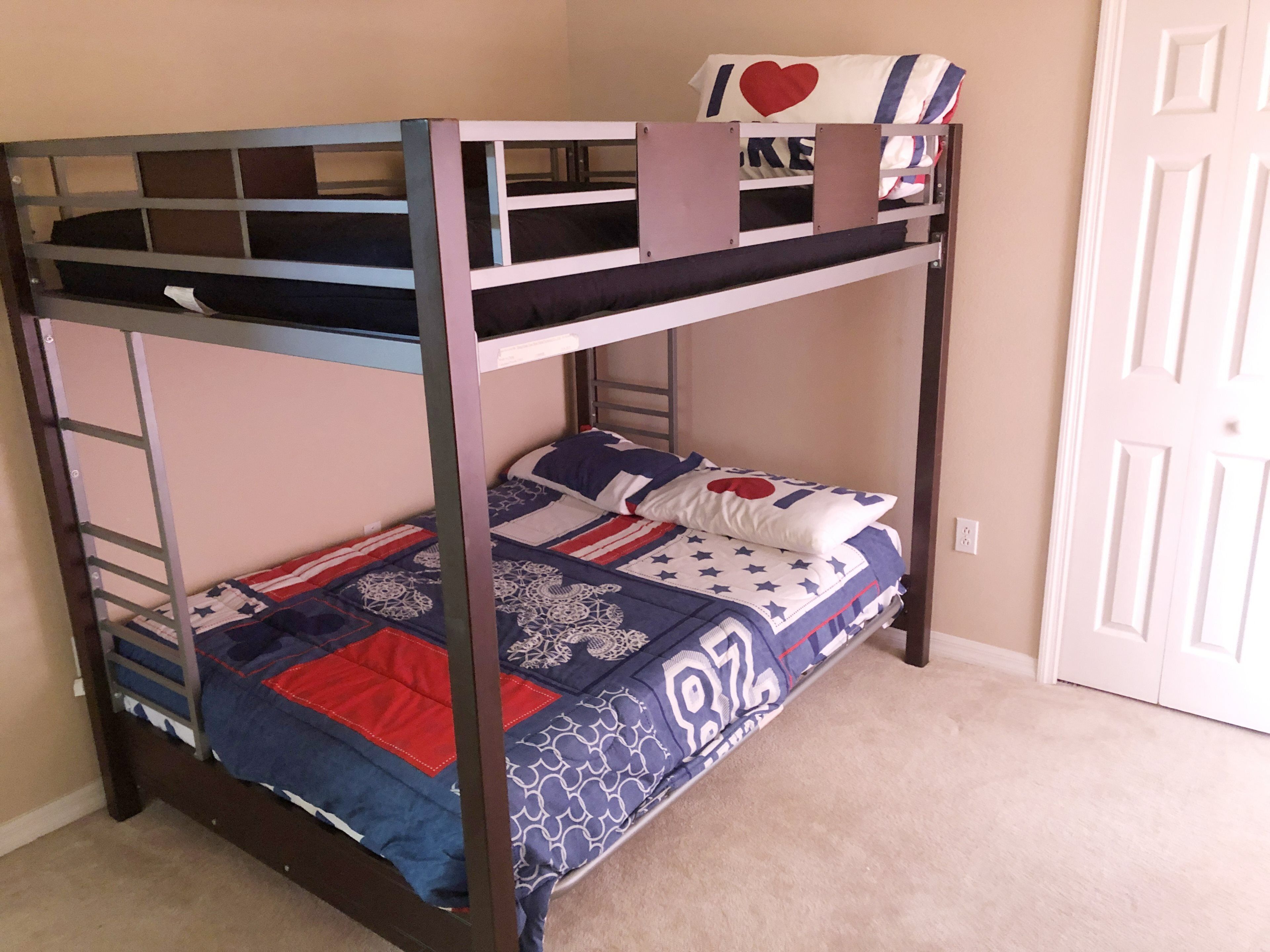 Un lit superposé avec une courtepointe matelassée, des oreillers et une échelle.