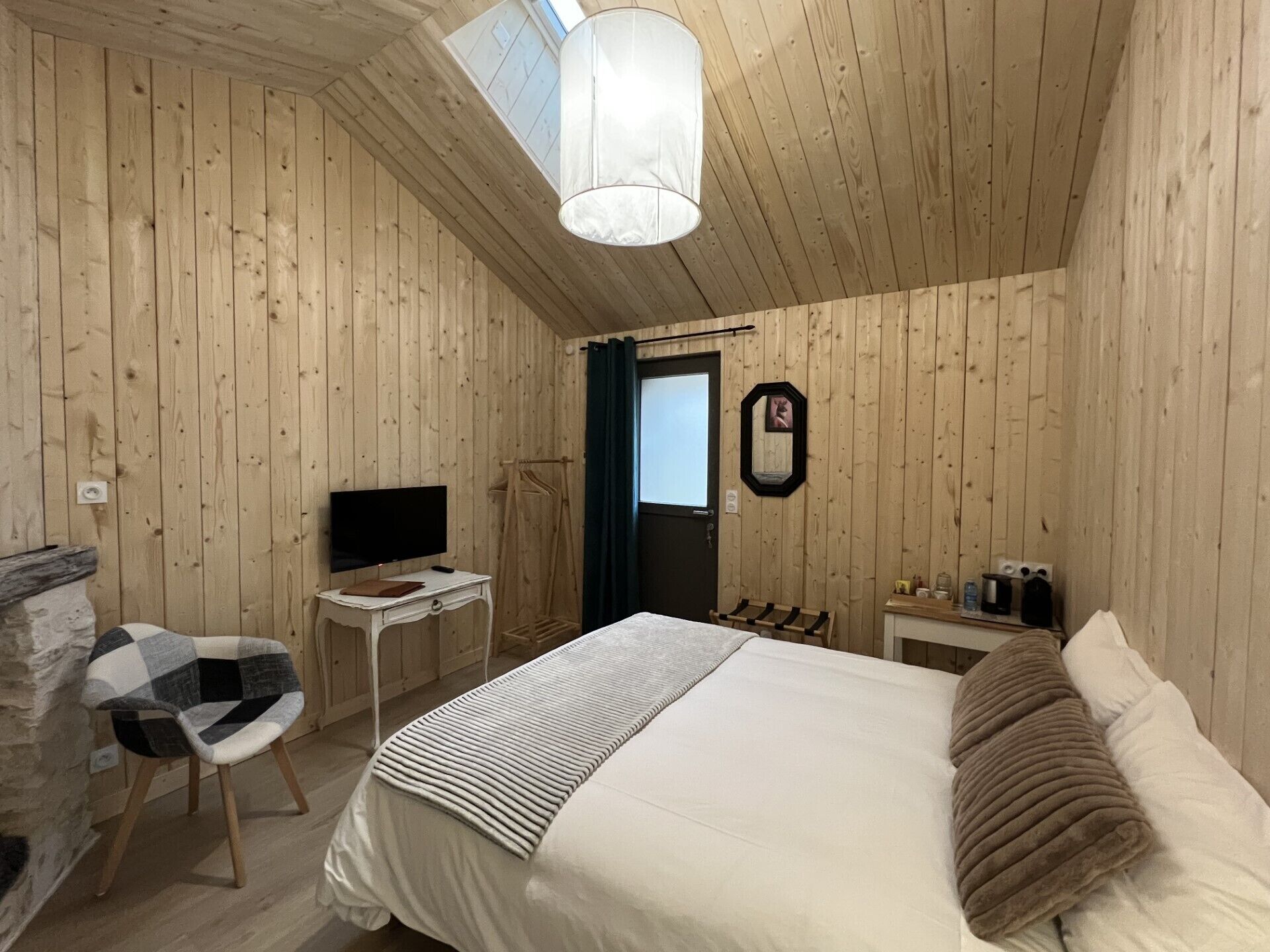 Habitación con paneles de madera, una cama, un televisor, un escritorio y una silla.