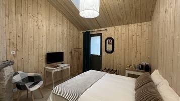 Habitación con paneles de madera, una cama, un televisor, un escritorio y una silla.