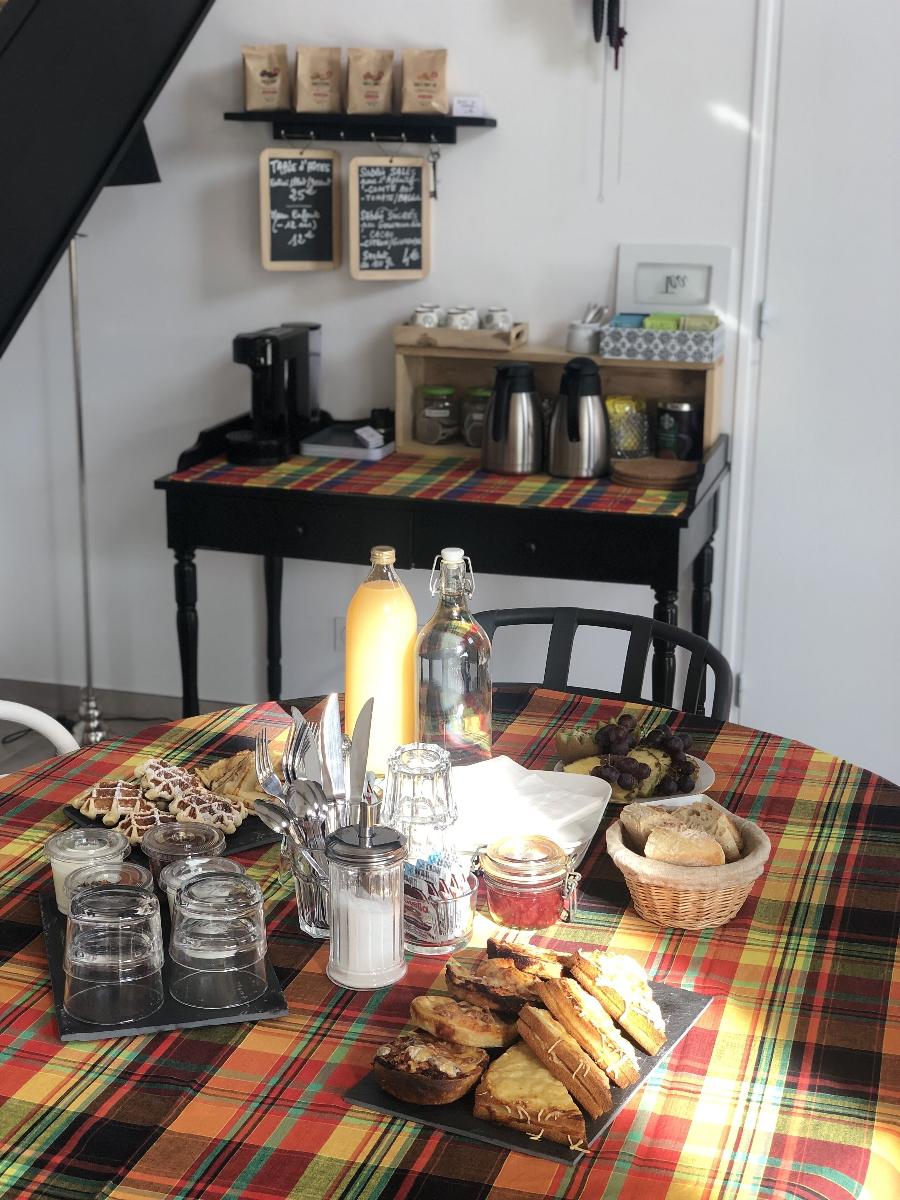 A table set with various food items and condiments, a coffee machine, and a chalkboard menu in the background.
