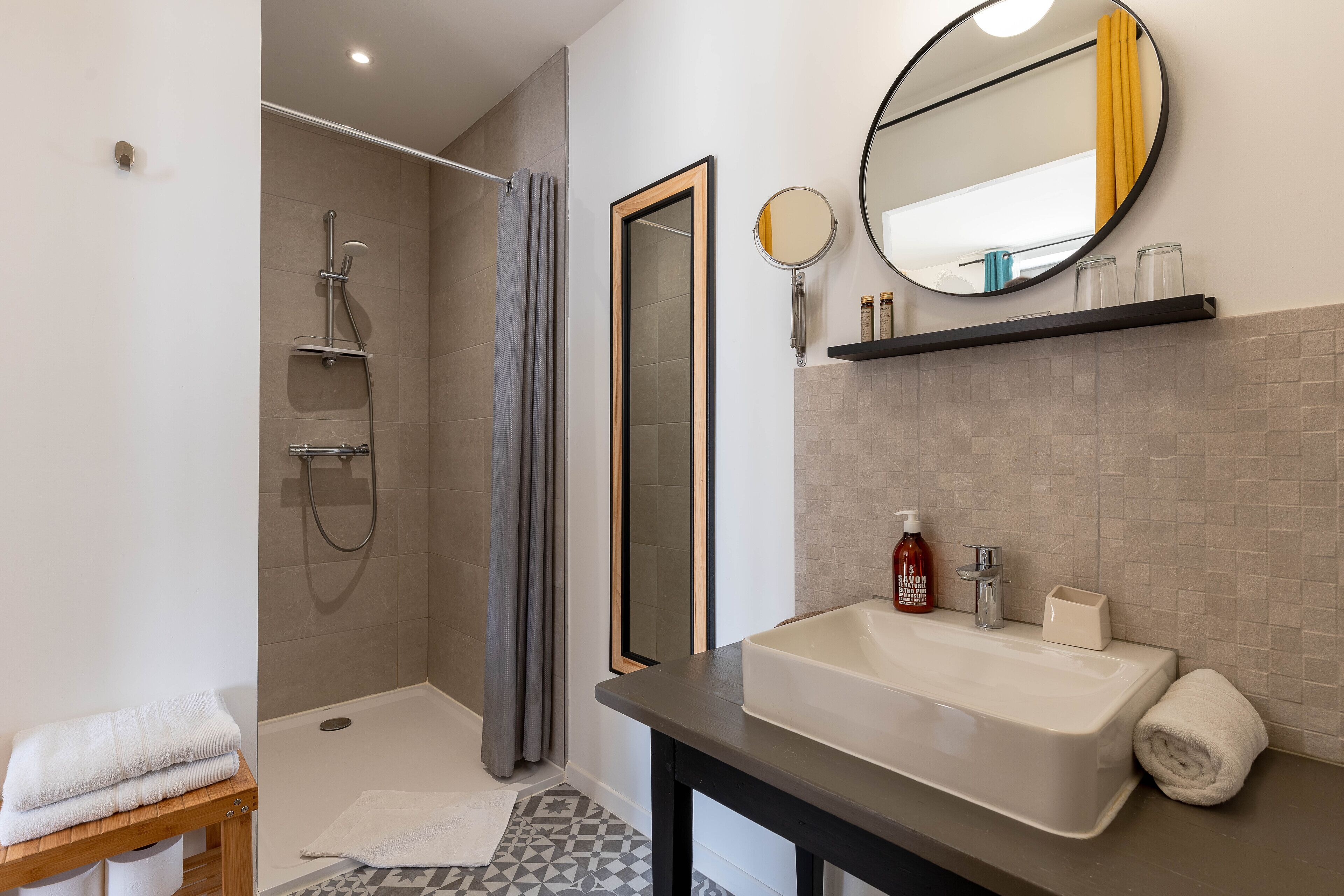 Un baño moderno con ducha, lavamanos y espejo.