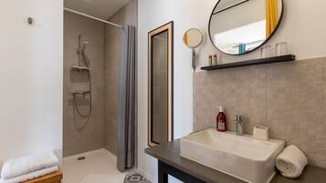 Un baño moderno con ducha, lavamanos y espejo.