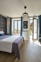 Quarto com cama, mesa de cabeceira, penteadeira, janela com cortinas e vista para o exterior.
