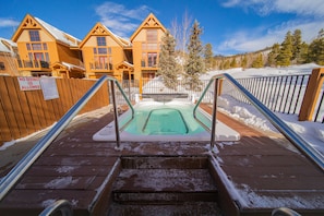 A hot tub area with wooden steps leading up to it, surrounded by a wooden fence and snow-covered ground. - Antlers Gulch 401 (Keystone)