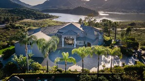 Une grande maison dotée d’un vaste jardin, d’une piscine et offrant une vue sur un lac et des montagnes.