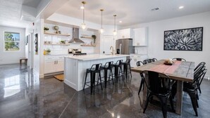 Una cocina moderna con una isla central, taburetes de bar y una mesa de comedor con sillas.